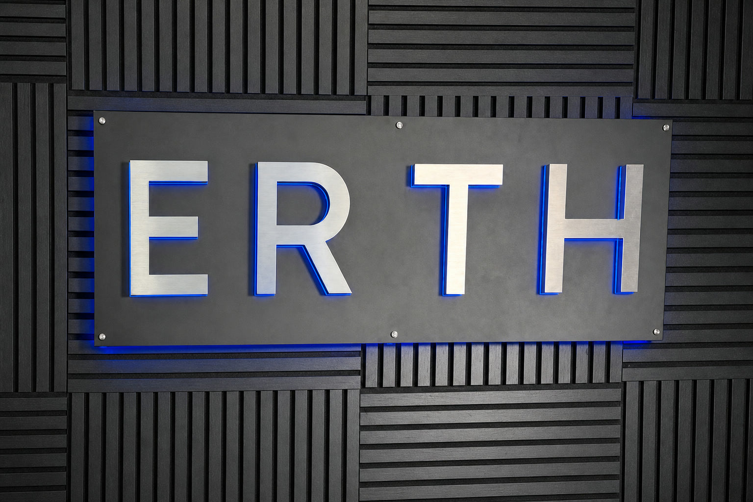Customer-installed ERTH logo sign with blue halo lighting on a backboard